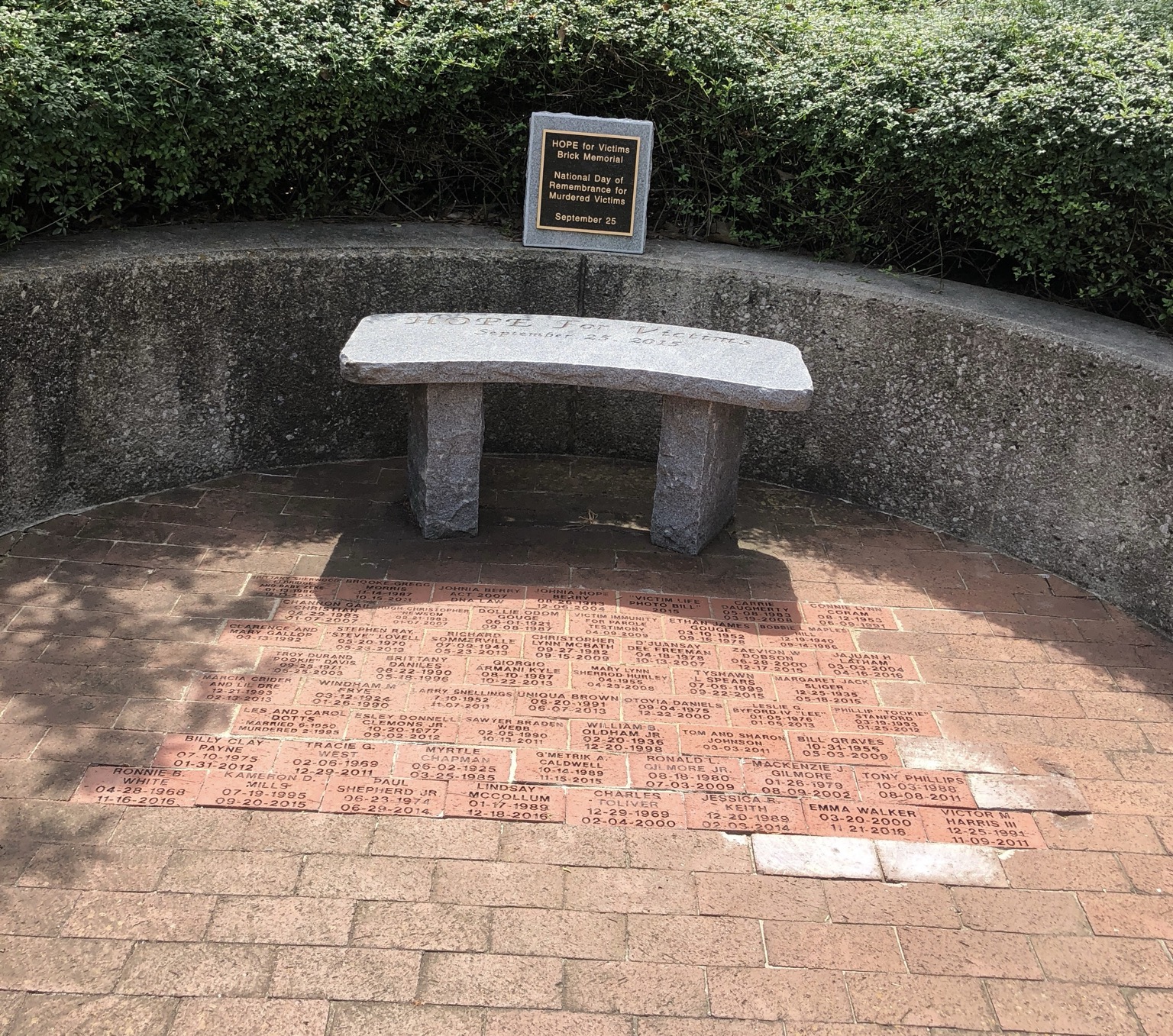 The Hope for Victims brick memorial: a curved stone bench above rows of engraved memorial bricks